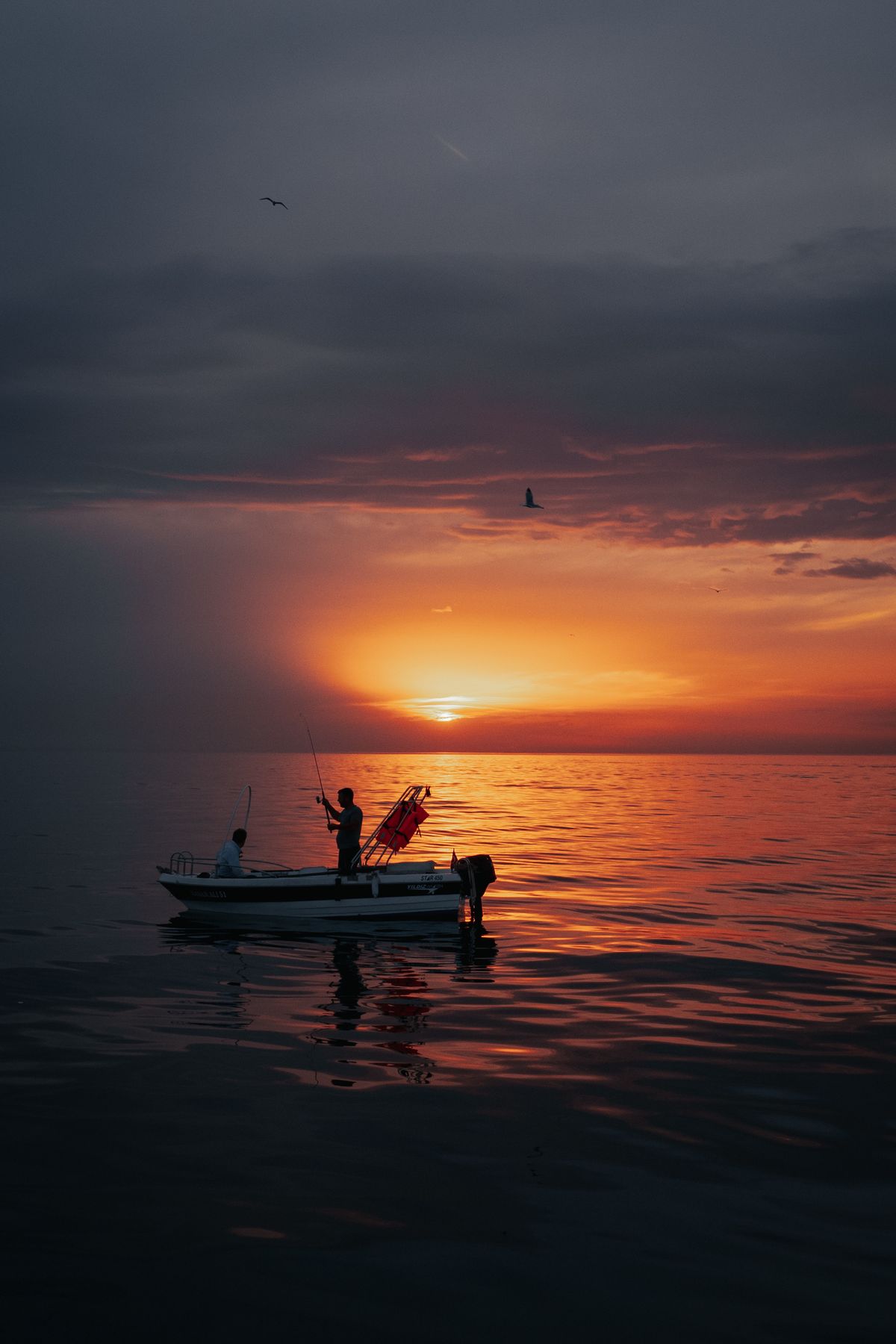 Twee vissers op een boot tijdens een visreis bij zonsondergang